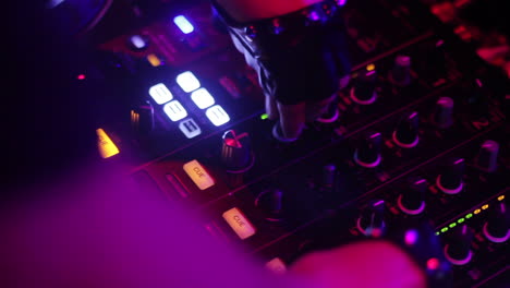 a dj mixing music on a console with vibrant club lights