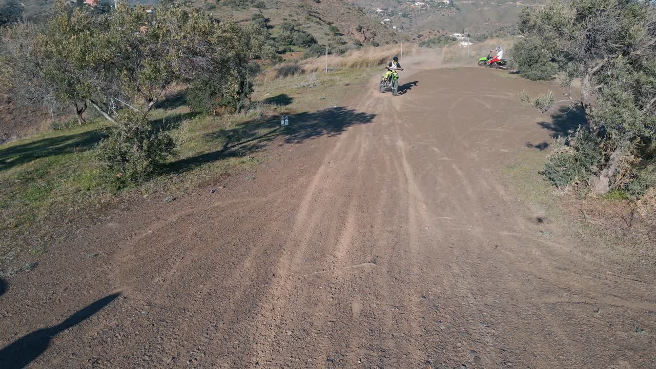 화창한 날 모터크로스 경주와 오토바이 라이더가 카메라를 향해 모퉁이를 빠져나가는 동안 말라가 스페인의 모터크로스 트랙의 정적 공중 드론 샷