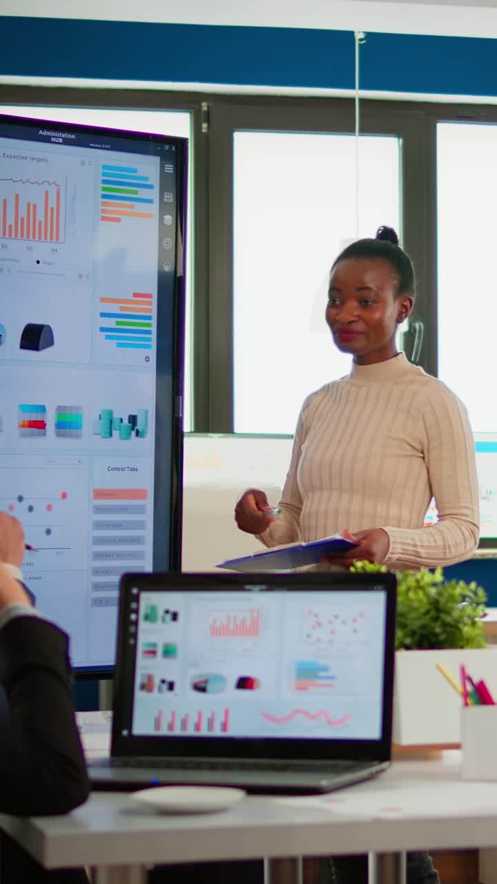 Vertical video Black woman worker explaning company statistics in front of colleagues