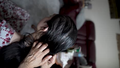 view of back head of female getting oil massaged into her hair and scalp