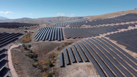 avión no tripulado sobre enormes paneles de energía solar fotovoltaica parque fila colinas panorámica hacia abajo