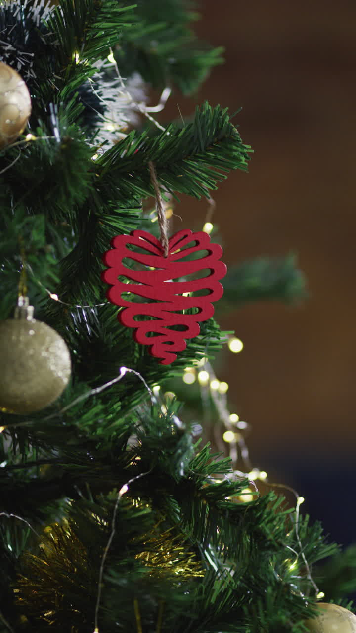 un primer plano vertical de un ornamento navideño en forma de corazón rojo en un árbol