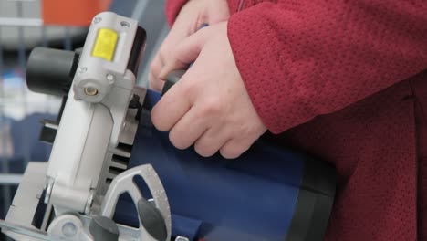 girl in a shop buys a big hand held, electric circular saw