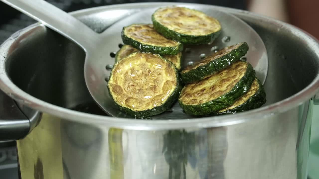 Close up shot of a spoon stirring boiled green zucchini with butter presentation