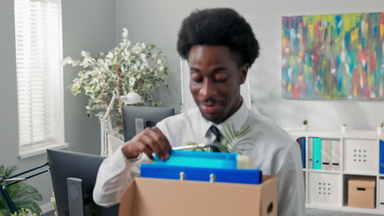 handsome men in white shirt with afro hair quits corporate job, walks out of office with things packed in box, quits corporate, quits responsibilities, retires, leaves social room, happy