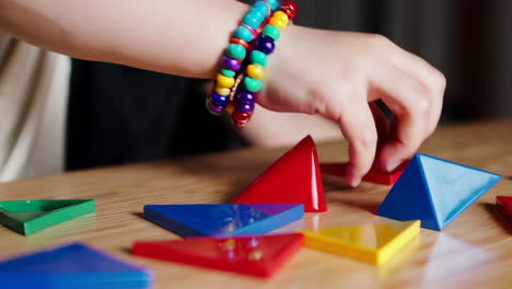 child's hand playing with colorful geometric building blocks