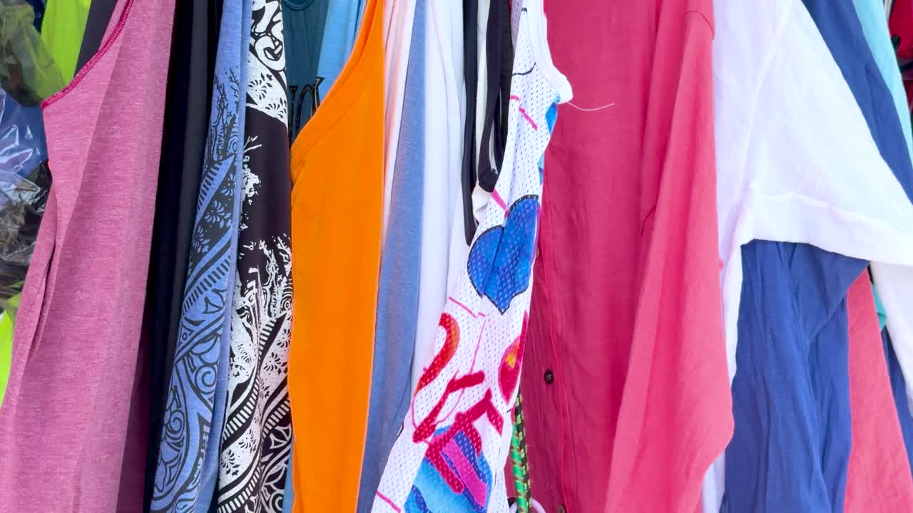 Close-up shot of vibrant resort wear hanging on a rack at a tropical street market