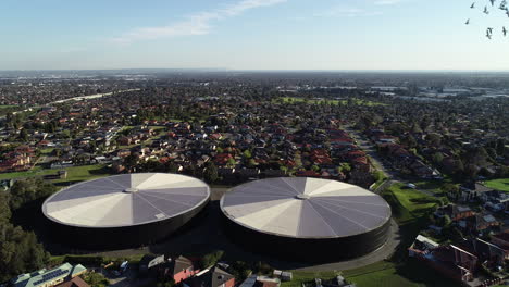 large water storage facility in the middle of neighborhood suburban sprawl while a flock of birds circles the aerial perspective