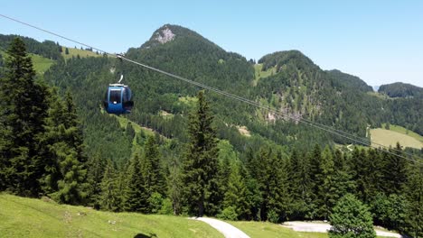 several cabins of a cable car driving up and down a mountain in the summer in the alps