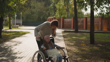 Mom leans to kiss face of little daughter in wheelchair