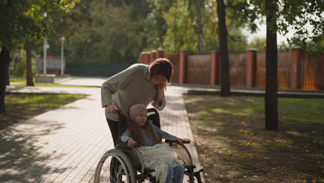 mom leans to kiss face of little daughter in wheelchair