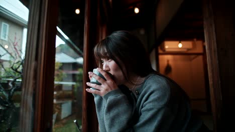 Woman Enjoying a Drink by the Window in a Japanese Cafe