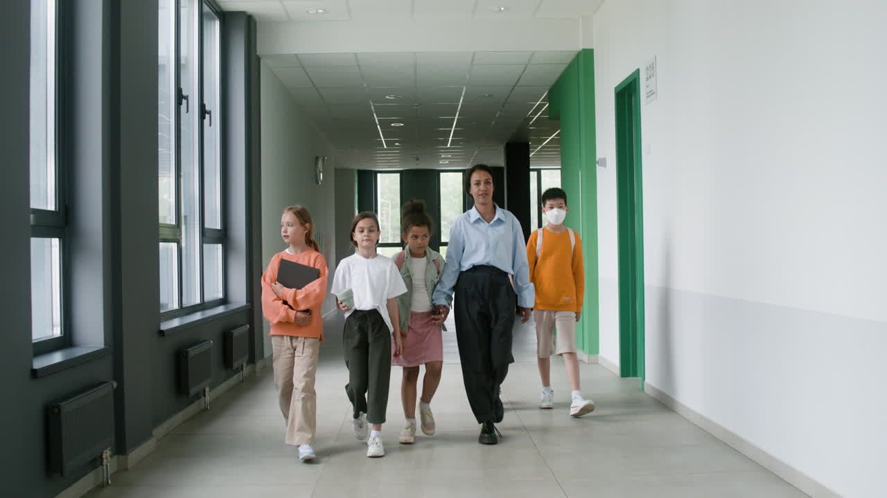 Teacher and pupils walking through the corridor.