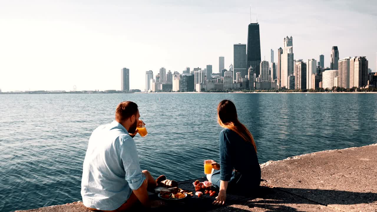 Happy couple enjoying beautiful landscape of Chicago, America on the shore of Michigan lake during picnic