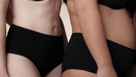 acercamiento de mujeres irreconocibles en ropa interior negra de pie uno al lado del otro