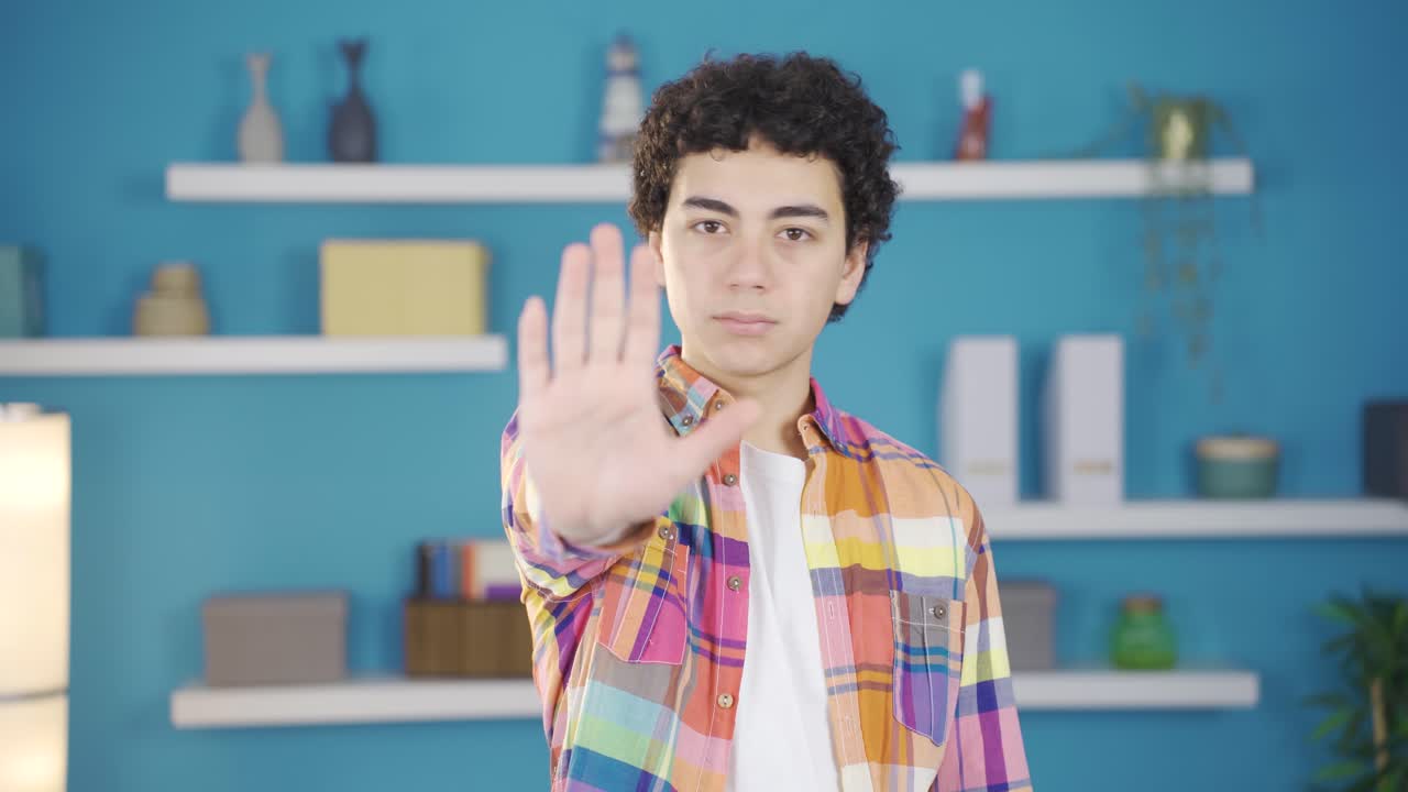 un chico extendiendo la palma de la mano a la cámara diciendo "alto".