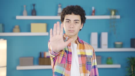 un chico extendiendo la palma de la mano a la cámara diciendo "alto".