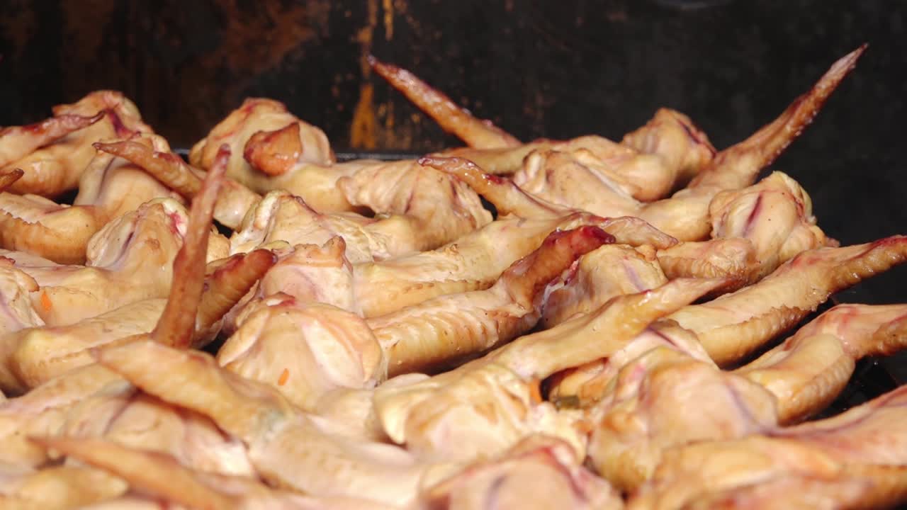 A large batch of golden-brown smoked chicken wings arranged on a grill rack. The wings appear juicy and well-cooked, ideal for barbecue or party servings.