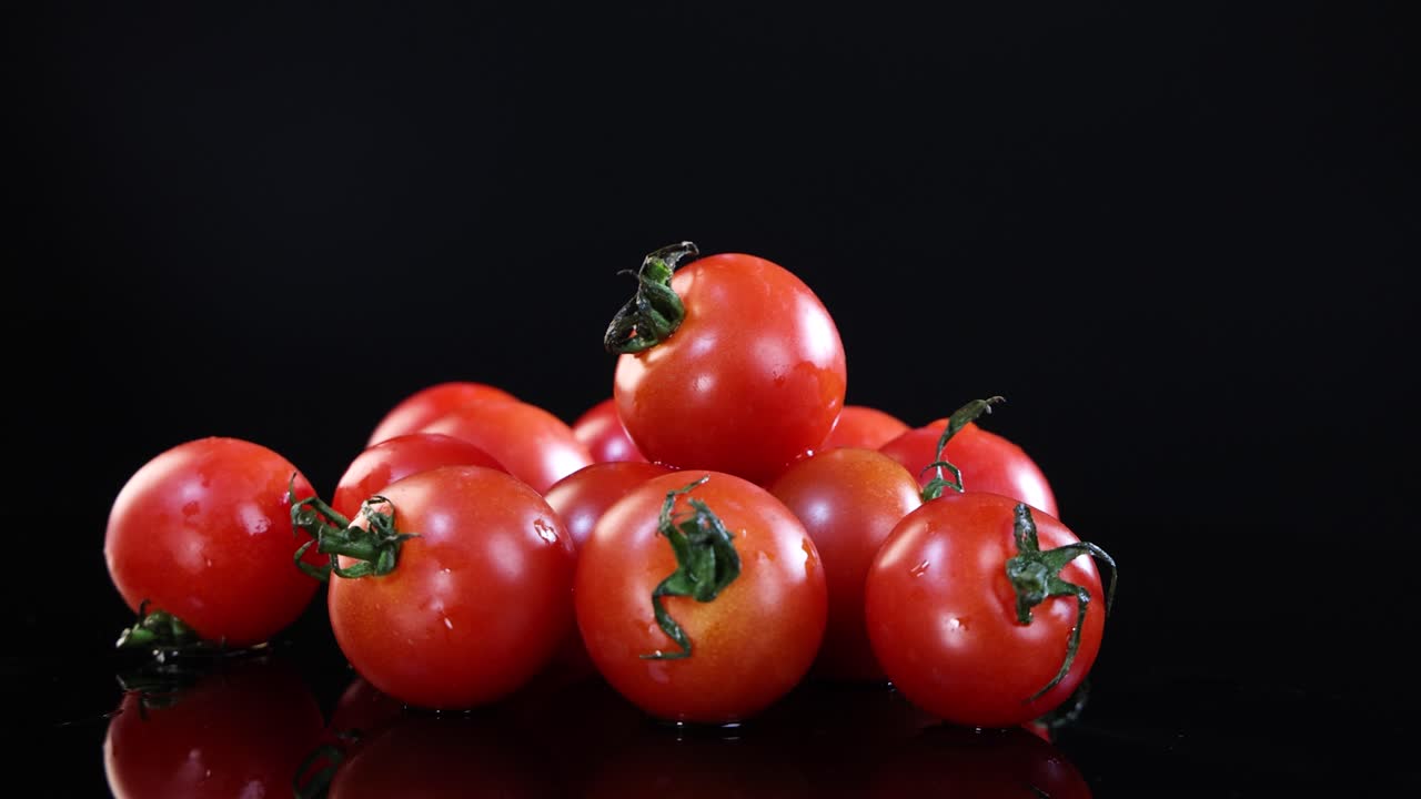 A cluster of ripe tomatoes rotates smoothly against a dark backdrop, highlighting their vibrant color and glossy texture