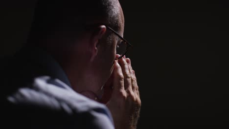 close up of depressed mature man struggling with mental health sitting in darkness in real time with low key lighting 6