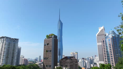 Ascending-Reveal-Behind-Foliage-Of-Famous-Merdeka-Tower-In-Kuala-Lumpur,-Malaysia