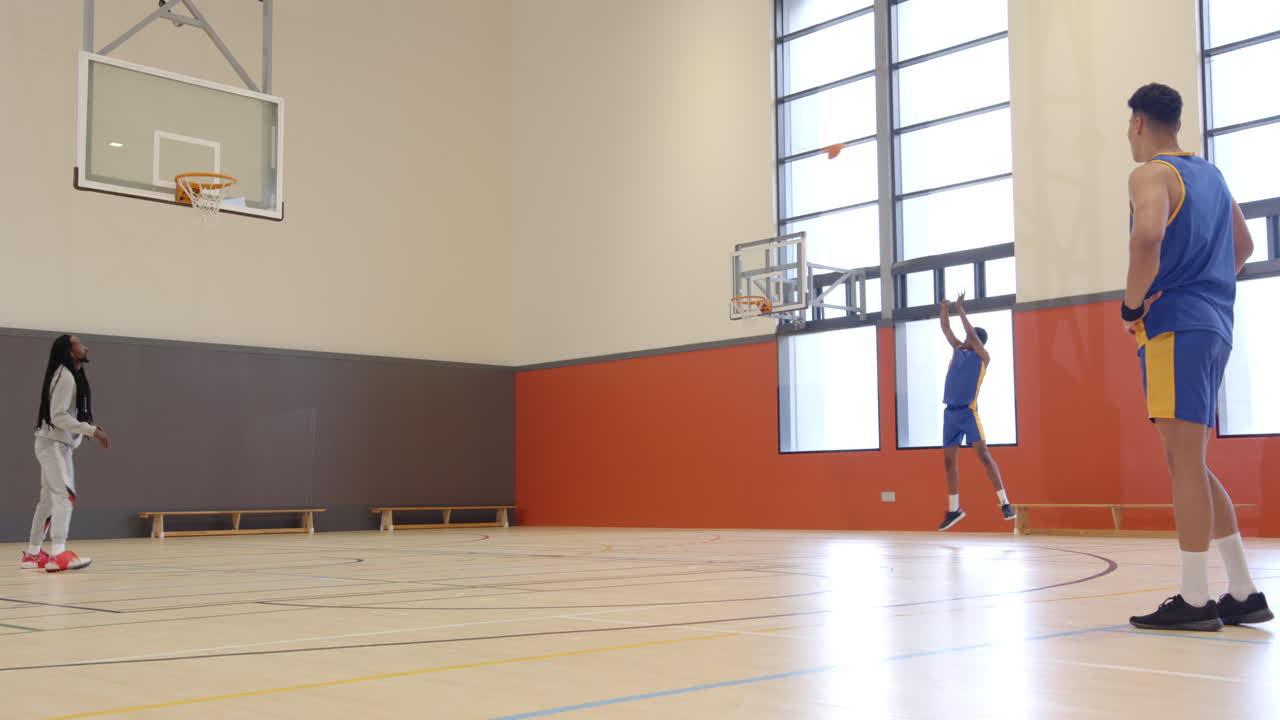 Playing basketball, two men practicing shooting drills in indoor court