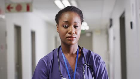 video portrait of african american female doctor smiling in hospital corridor, copy space