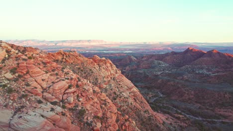 Stunning-Aerial-Reveal-of-Red-and-Orange-Mountains-and-a-Green-Valley-in-Yant-Flats,-Utah-at-Sunset-near-St