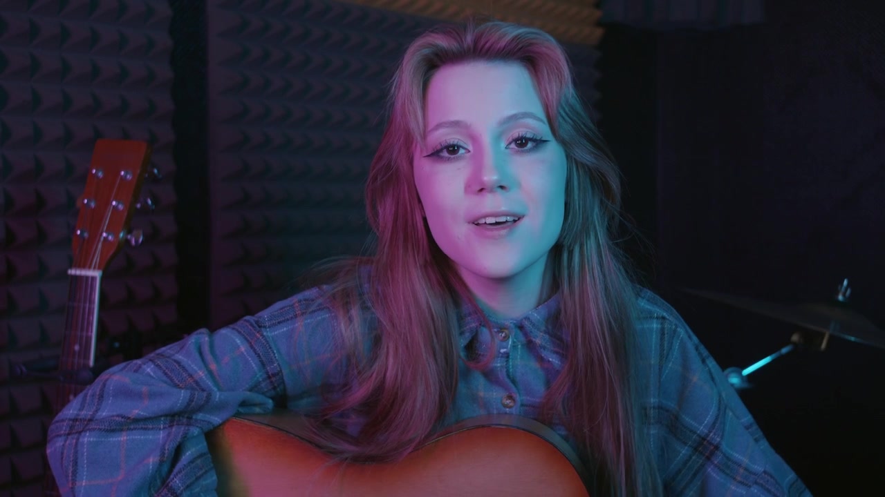 Giovane donna attraente che suona la chitarra in uno studio di registrazione