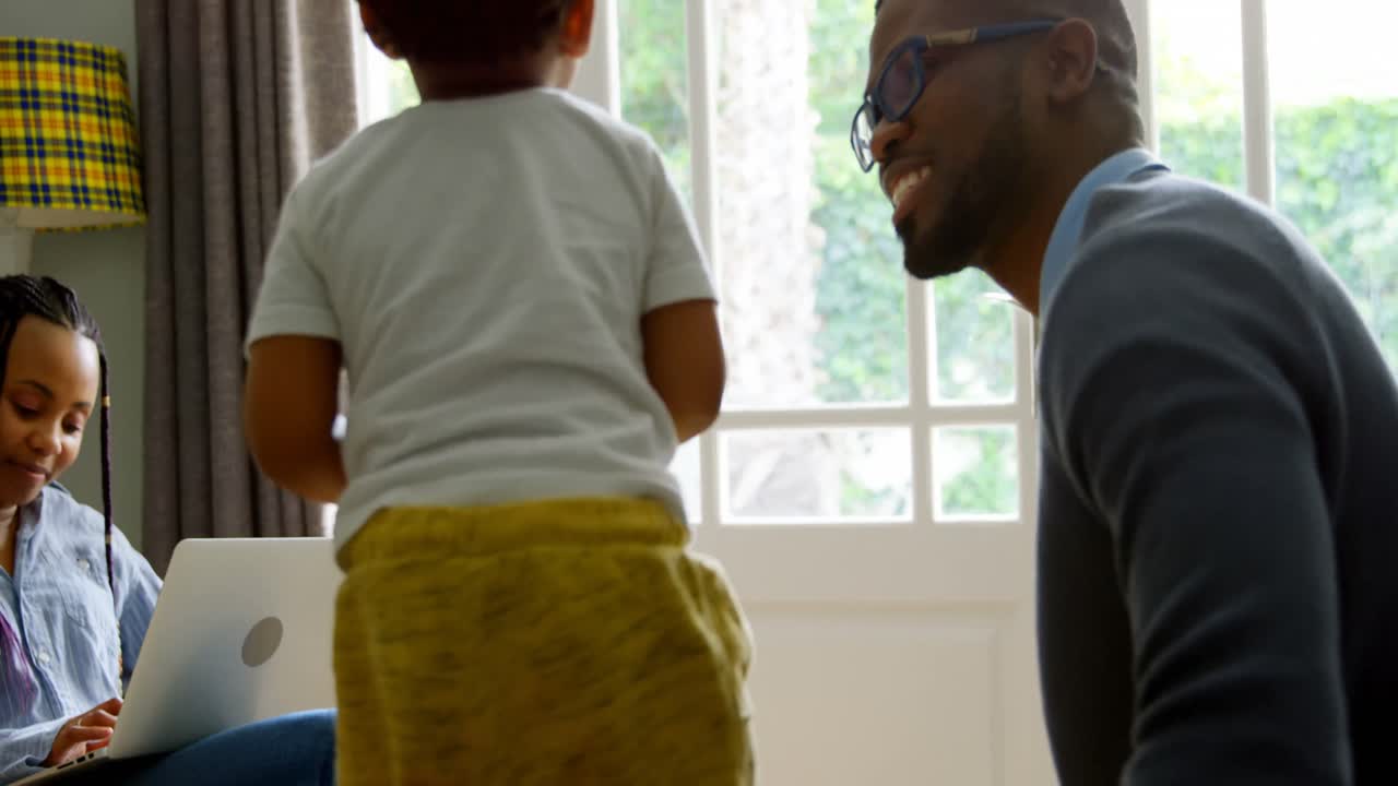 vista lateral de un joven padre negro jugando con su hijo en la vida de una casa cómoda 4k