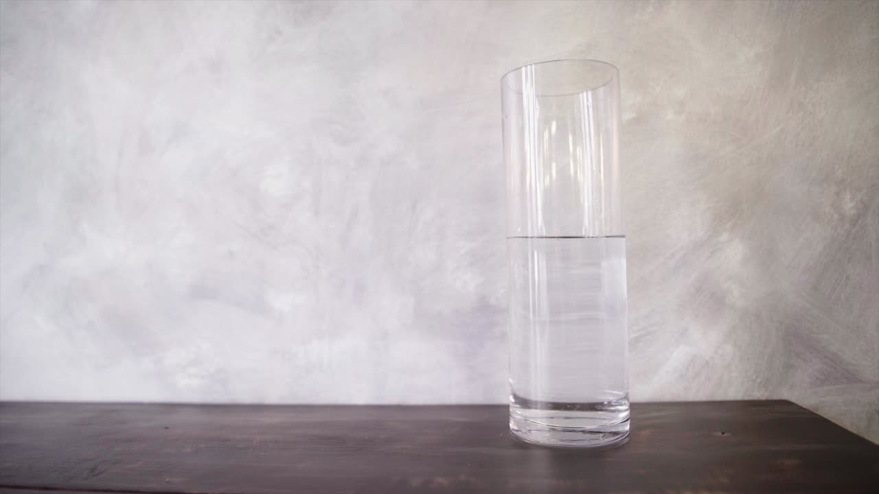 나무 탁자 위의 높은 유리 그릇에 물 한 병