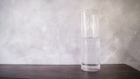 una botella de agua en el vaso alto de la mesa de madera