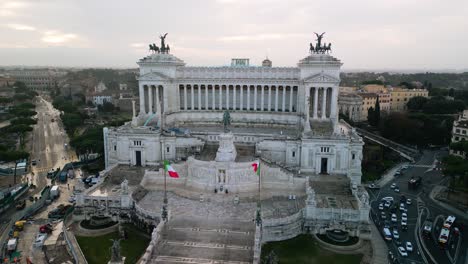 Hermosa-Vista-Aérea-Orbital-Sobre-La-Plaza-Venezia,-El-Altar-De-La-Patria-Con-El-Coliseo-Romano-Al-Fondo