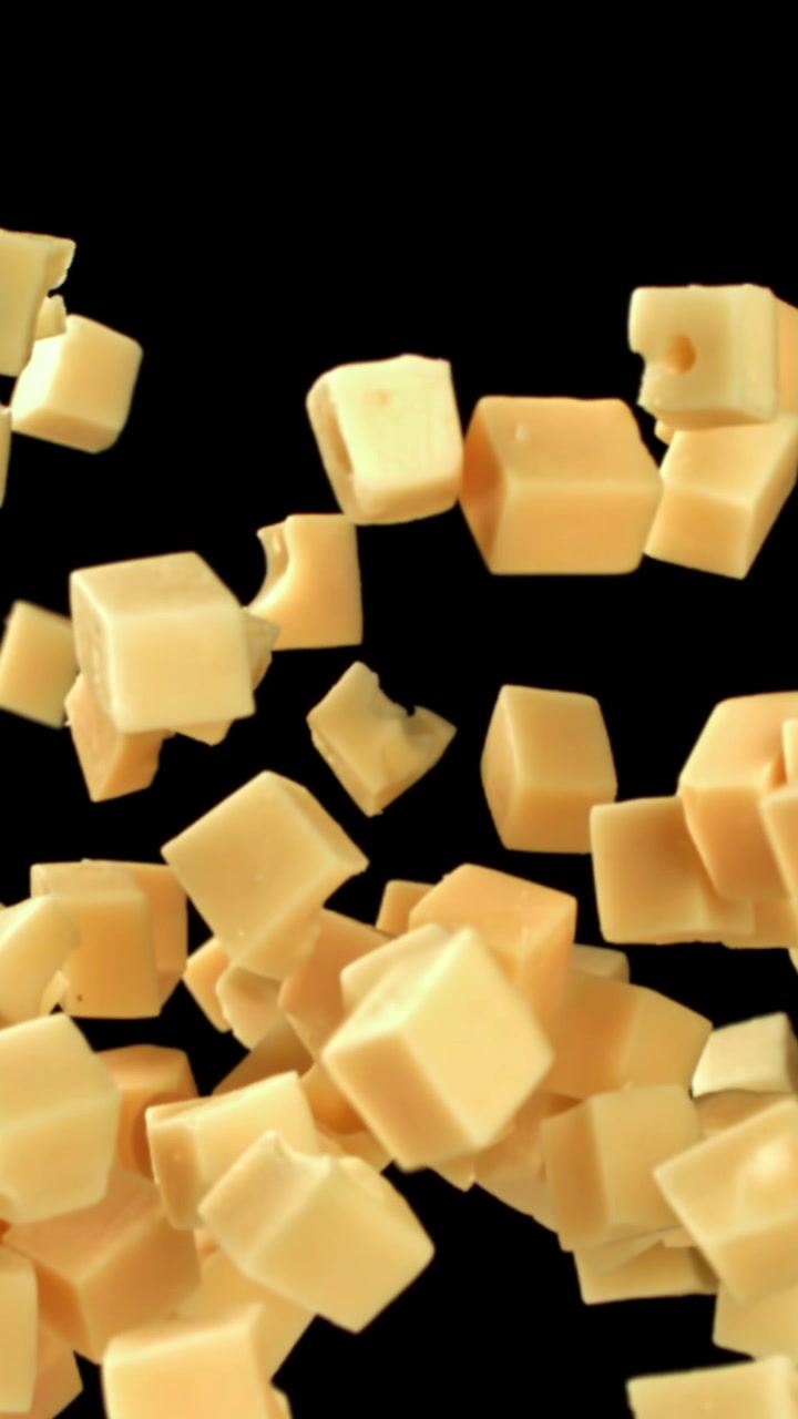 Ralenti de cubes de fromage tombant sur fond noir