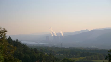 Schornsteine-Eines-Kernkraftwerks-Auf-Dem-Land-Mit-Fluss-Und-Hügeln-In-Frankreich-In-Zeitlupe-Bei-Sonnenuntergang-Mit-Stromleitungen