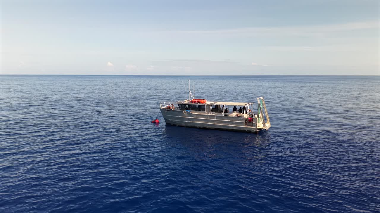 Tour boat anchored alone in the deep blue ocean off the coast of Oahu at Sunrise