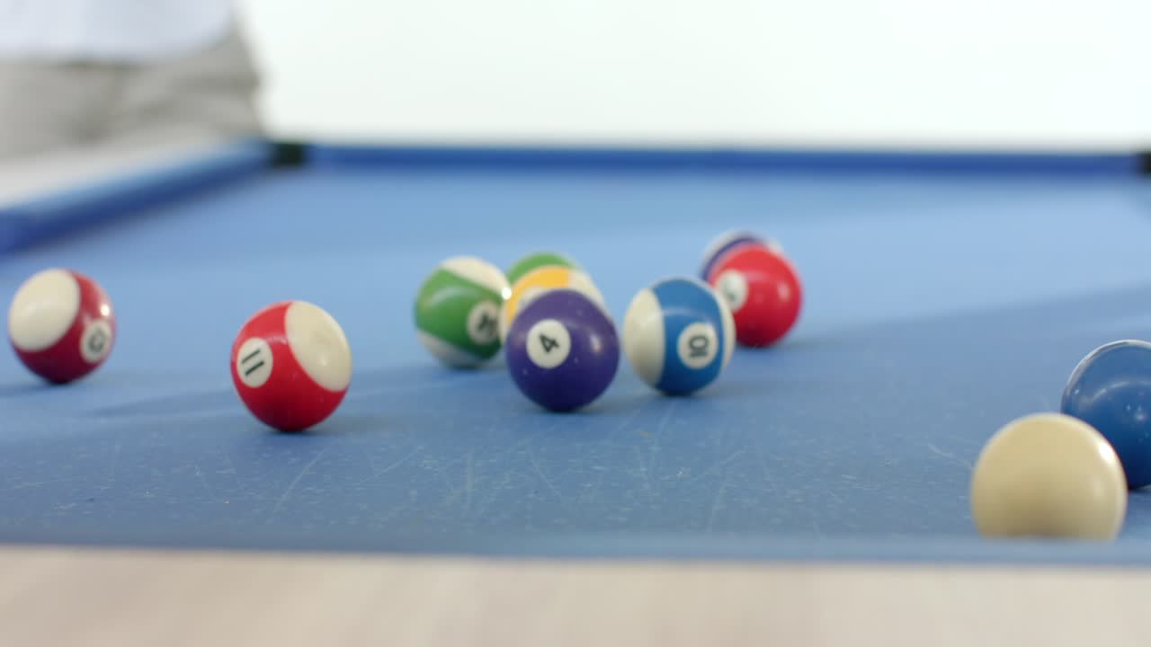 Female friends breaking rack on pool table at home after placing cue ball to start game