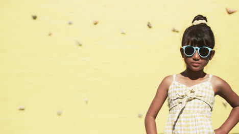 In-a-school-setting,-a-young-biracial-student-stands-before-a-yellow-background-with-copy-space