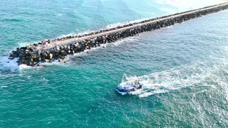 trawler navigates ocean near rocky seaway