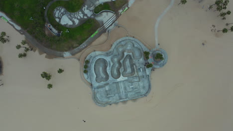 AERIAL:-Birds-View-180-degree-turn-over-Venice-Beach-Skate-Park,Los-Angeles,-California-Cloudy