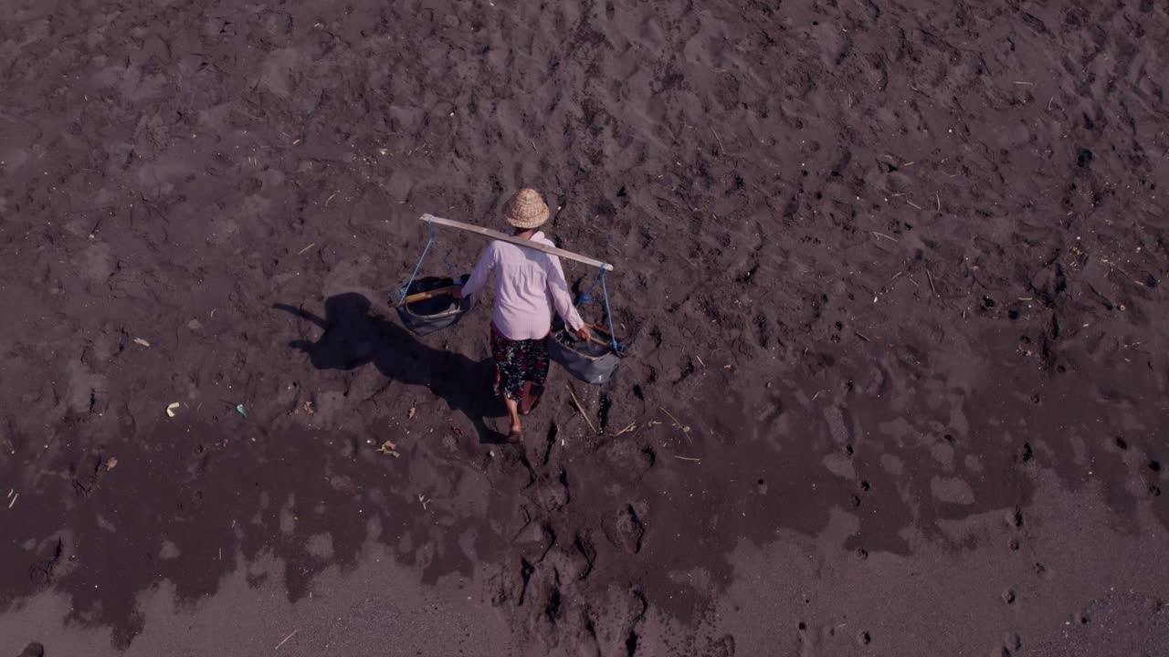 Produzione tradizionale di sale su spiaggia di sabbia nera a Klungkung