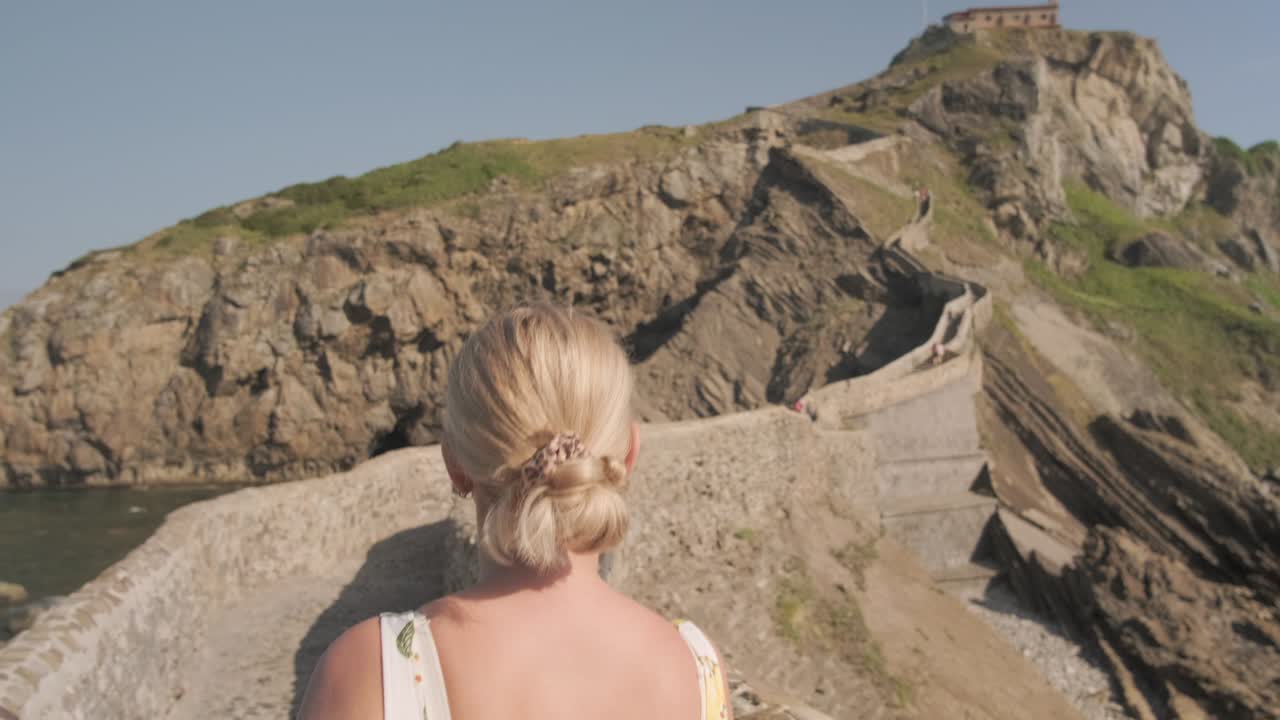 женщина-путешественник, идущая в одиночку по мосту в кастелугатсе в испании под солнцем.