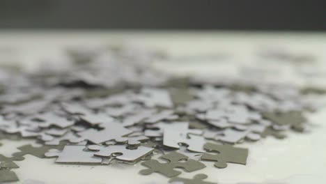 slow motion of water dripping on white and gray puzzle pieces laying randomly on a white surface. shot in 4k;  shallow depth of field. smooth camera sliding movement.