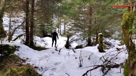 girl in winter clothes running, jumping and having fun through the forest covered in white snow during her workout