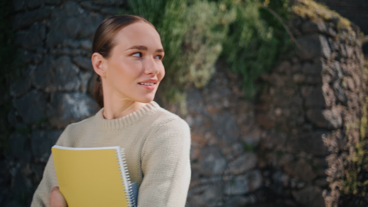 Ritratto di insegnante sorridente in posa in un parco cittadino. Studentessa che tiene in mano un libro