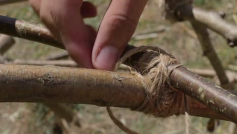 bushcrafter tying a knot on a wooden construction