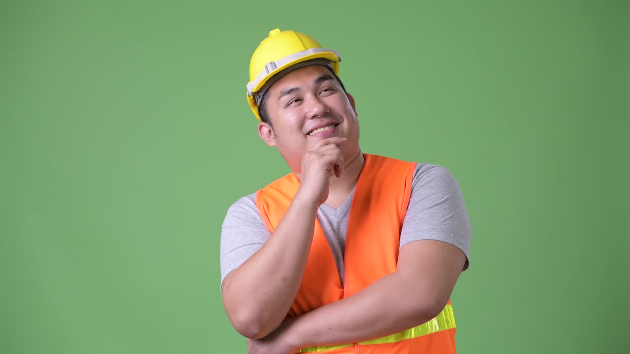 젊은 잘생긴 과체중 아시아인 남자 건설 노동자 초록색 배경