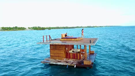 aerial drone shot over the manta resort underwater hotel in tanzania africa with a man and woman lounging on the platform over the ocean 1