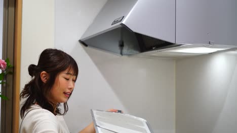 woman removing the filter of the ventilation fan