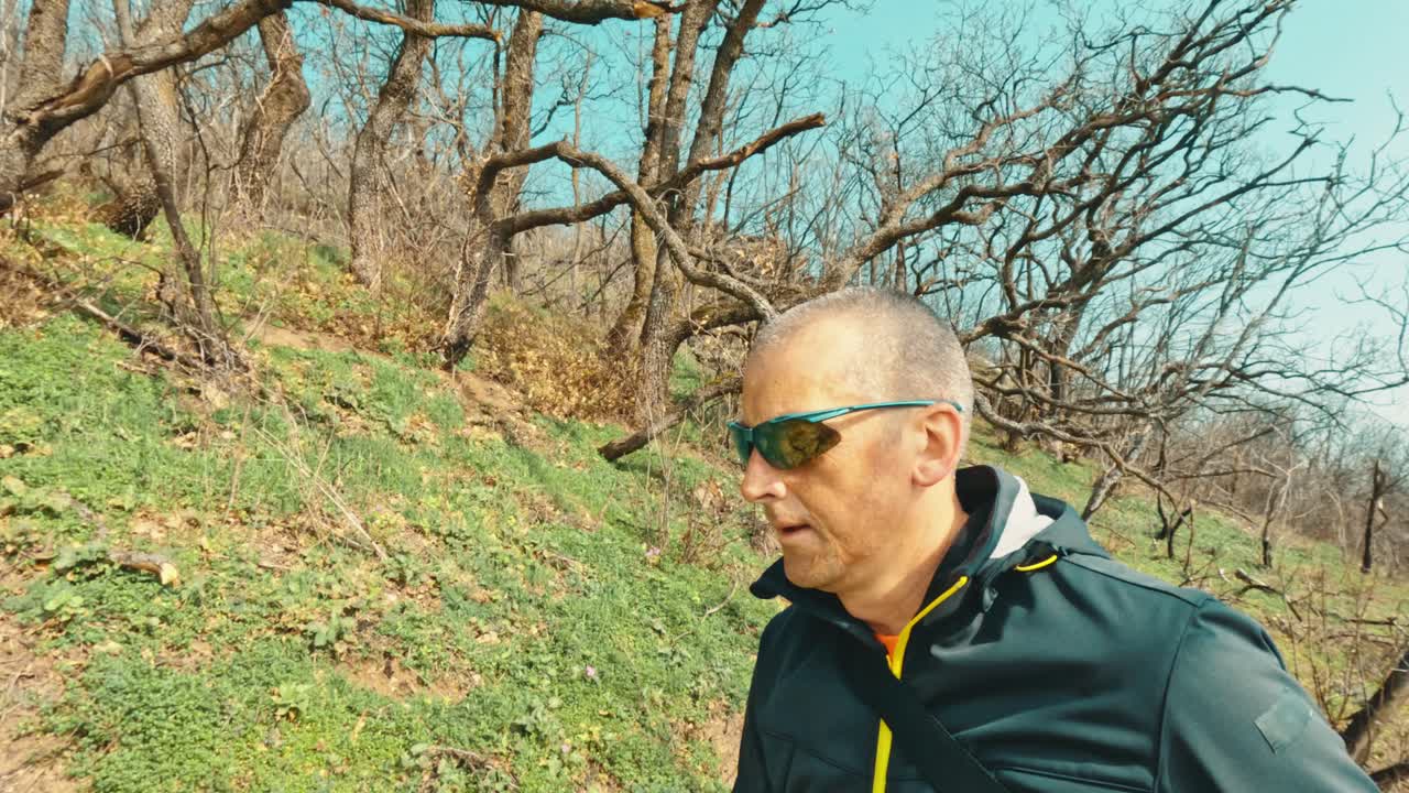 An active senior man enjoying a brisk walk through the spring woods. Concept of healthy aging, retirement lifestyle, and cardiovascular exercise in nature
